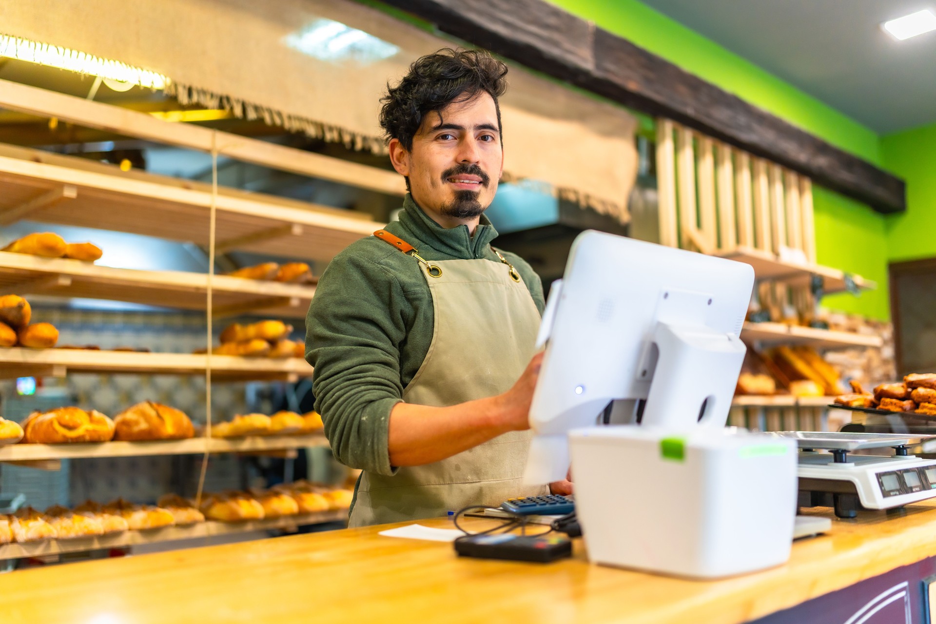 Salesman using computer stranding at counter of a bakery shop